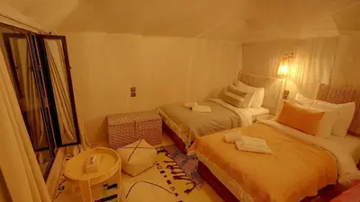 a hotel room with two beds and a window at Arabian Nights Desert Camp Merzouga in Lac Yasmins