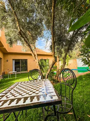 a table and chairs sitting in the grass in a yard at Villa à ourika, piscine et montagnes, 40 min Marrakech in Ourika
