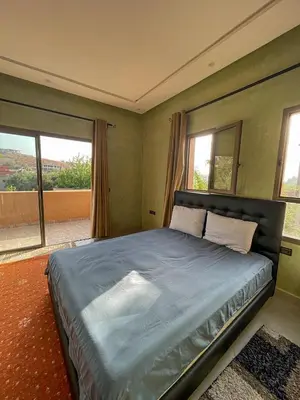 a bedroom with a large bed in a room with windows at Villa à ourika, piscine et montagnes, 40 min Marrakech in Ourika