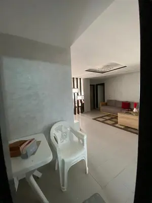 a living room with a white table and a chair at Appartement lux meublé in Ouarzazate