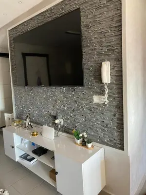 a bathroom with a sink and a tv on a brick wall at Appartement lux meublé in Ouarzazate