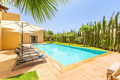 a swimming pool with lounge chairs and an umbrella at Villa Maryam , Élégance et calme & piscine privée in Marrakech
