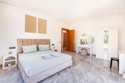 a white bedroom with a bed and a mirror at Villa Maryam , Élégance et calme & piscine privée in Marrakech
