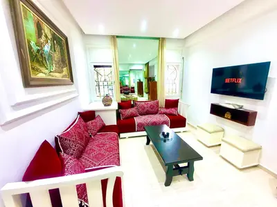 a living room with red couches and a tv at Charmant appartement avec Wifi in Fès