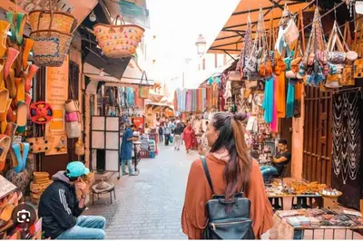 a woman walking down a street in a market at Charmant appartement avec Wifi in Fès