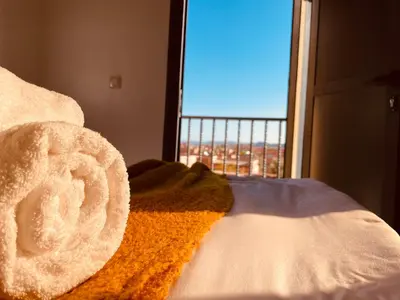 a bed with a view of a city from a window at ZyonFamily in Ouarzazate