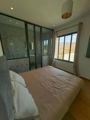 a bedroom with a large bed with a large window at Maison blanche in Sbiti