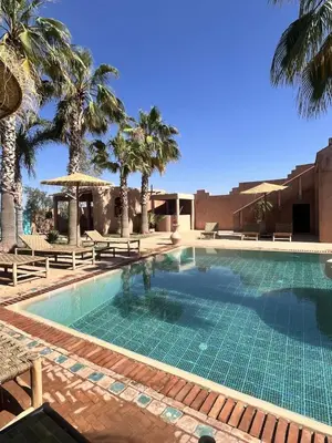 a swimming pool with palm trees and a building at Villa 4 chambres avec grande piscine privée in Marrakech