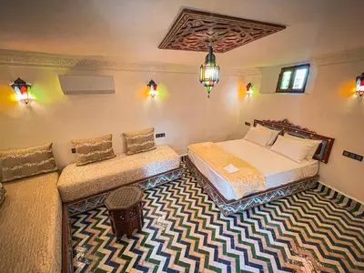 a bedroom with two beds and a chandelier at Dar Roots Fes Ziat in Fès