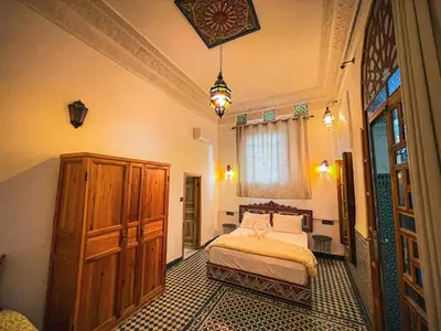a bedroom with a bed and a wooden cabinet at Dar Roots Fes Ziat in Fès