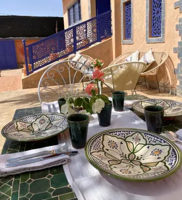 a table with plates and flowers on top of it at Shams Ourika in Sbiti