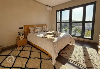 a bedroom with a large bed with a large window at Shams Ourika in Sbiti