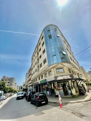 a tall building with cars parked in front of a street at Appartement de luxe à Tanger in Oulad Akkou