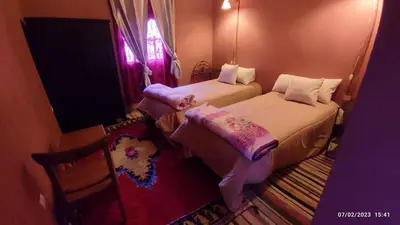 two beds in a small room with a window at Gite famille saghir in Skoura