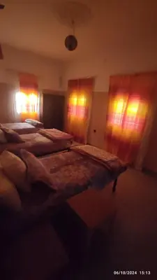 a bedroom with three beds in a room with windows at Gite famille saghir in Skoura
