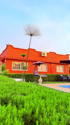 a red house with a bird sitting in the grass at Villa Dayet Roumi House in Friday Market