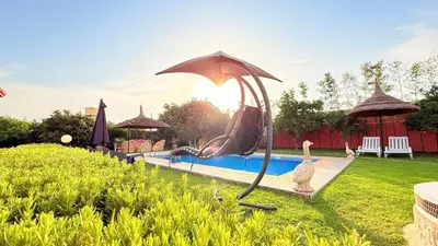 a swimming pool with a umbrella in a yard at Villa Dayet Roumi House in Friday Market