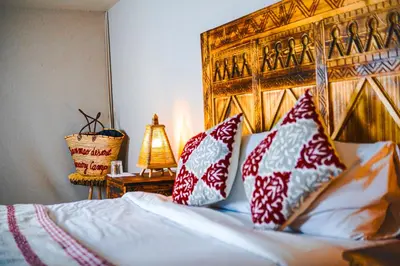 a bedroom with a bed with red and white pillows at Aisha VIP Camp in Merzouga