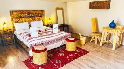 a bedroom with a large bed with a red rug at Aisha VIP Camp in Merzouga