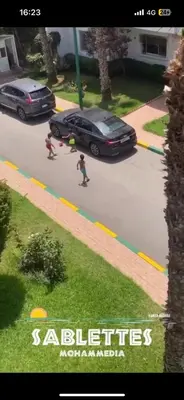 a group of children skateboarding down a street with a car at residence le litoral 1 in Oulad Akkou
