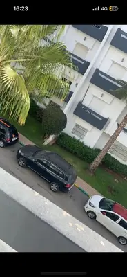 a black car and a white car parked in front of a house at residence le litoral 1 in Oulad Akkou