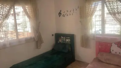 a room with a green couch and two windows at Appartement exceptionnel a louer in Oulad Akkou