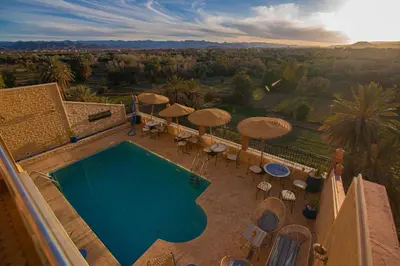 an aerial view of a swimming pool with umbrellas and chairs at Maison d'hôte IGRANE in Tinerhir