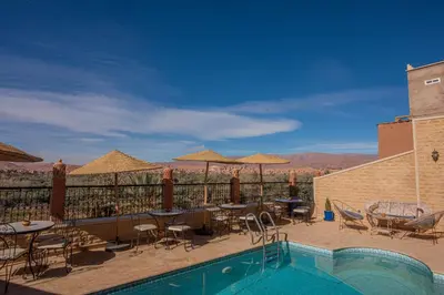 a resort with a pool and tables and chairs at Maison d'hôte IGRANE in Tinerhir