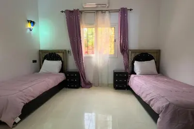 two beds in a room with purple curtains at Villa Jenane Rabia in Amezrou