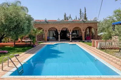 a swimming pool in front of a house with a building at Villa Jenane Rabia in Amezrou