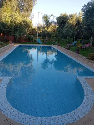 a swimming pool with blue water in a park at Villa Jenane Rabia in Amezrou