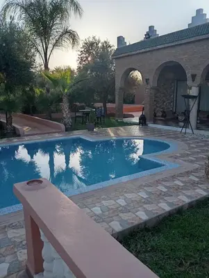 a swimming pool in a yard next to a house at Villa Jenane Rabia in Amezrou