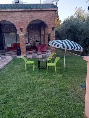a patio with two chairs and a table and an umbrella at Villa Jenane Rabia in Amezrou