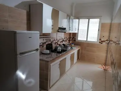 a kitchen with a white refrigerator and a counter at Aicha's appartement 1 in Meknès