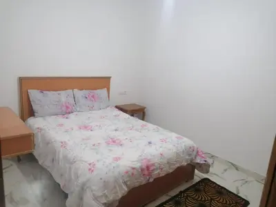 a bedroom with a bed with pink flowers on it at Aicha appartement 2 in Meknès