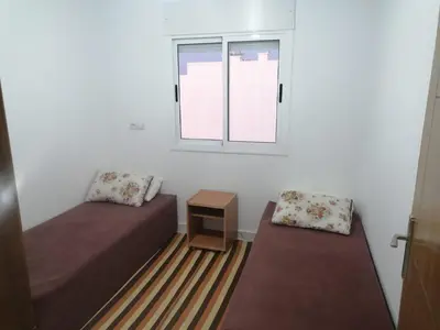 a small room with two beds and a window at Aicha appartement 2 in Meknès
