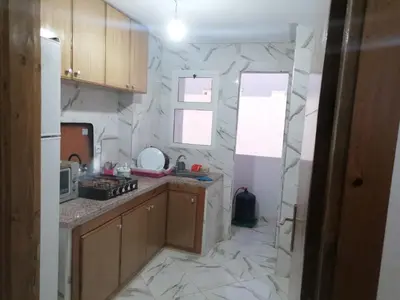 a kitchen with marble walls and wooden cabinets at Aicha appartement 2 in Meknès