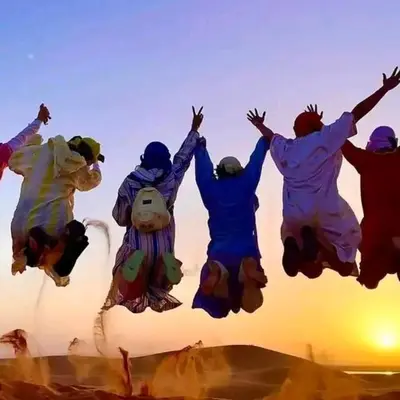 a group of people jumping in the air at ERG merzouga desert Luxury camp in Merzouga