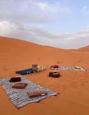 a group of blankets in the sand in the desert at ERG merzouga desert Luxury camp in Merzouga