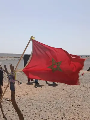 a boy holding a red flag on the beach at ERG merzouga desert Luxury camp in Merzouga