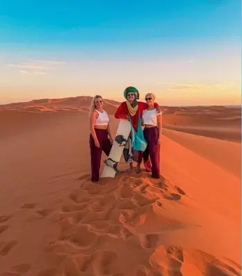 a group of three women standing in the desert at ERG merzouga desert Luxury camp in Merzouga