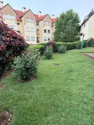 a yard with a building and some bushes and flowers at Dar Dina Havre de paix sous les cèdres d'Ifrane in Ifrane
