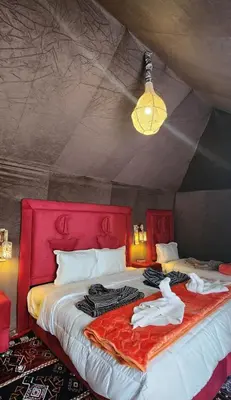a bedroom with a red bed with clothes on it at fabulousluxurycamp in Merzouga