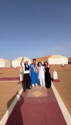 a group of people posing for a picture on a red carpet at fabulousluxurycamp in Merzouga