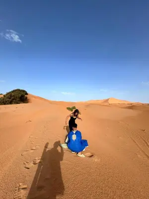 two people sitting in the sand in the desert at fabulousluxurycamp in Merzouga