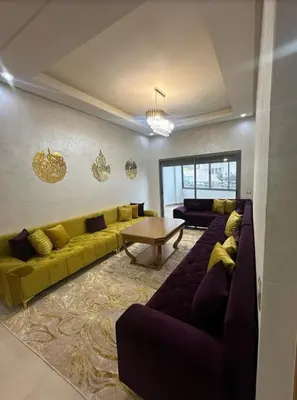 a living room with a yellow couch and a table at Mansbay Beach in Oulad Akkou