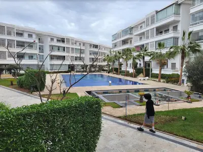 a young boy standing in front of a large apartment building at Mansbay Beach in Oulad Akkou