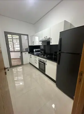 a kitchen with a black refrigerator and white cabinets at Mansbay Beach in Oulad Akkou