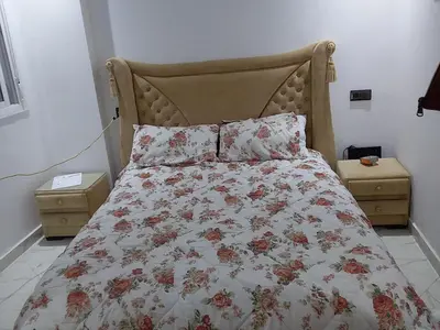 a bed with a floral comforter and two night stands at Appartement A Martil in Oulad Akkou