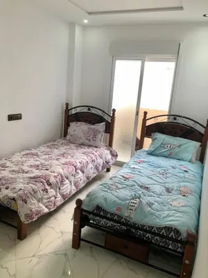 a bedroom with two beds and a window at Appartement A Martil in Oulad Akkou